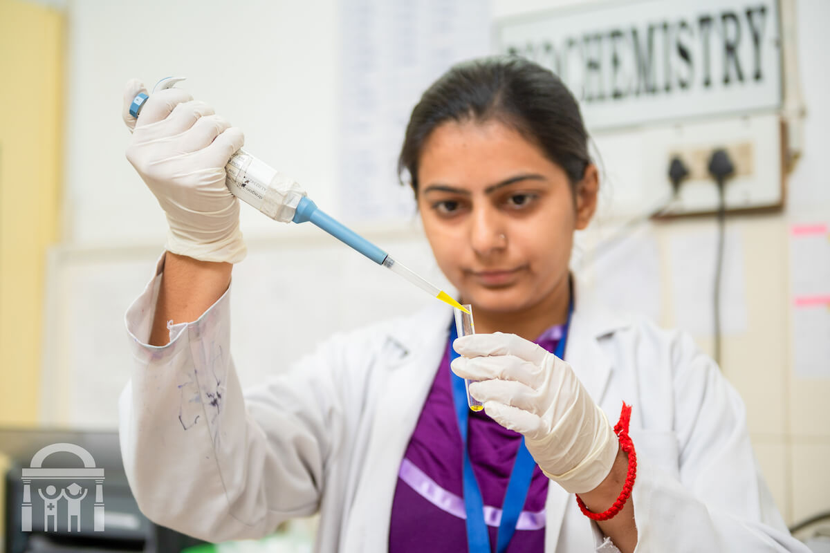 Lab technician squeezing fluid into tube in biochemistry pathology lab at Guru Nanak Mission Hospital near Banga in Punjab